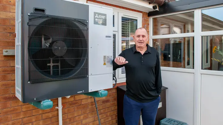 A man standing next to a newly installed air-source heat pump