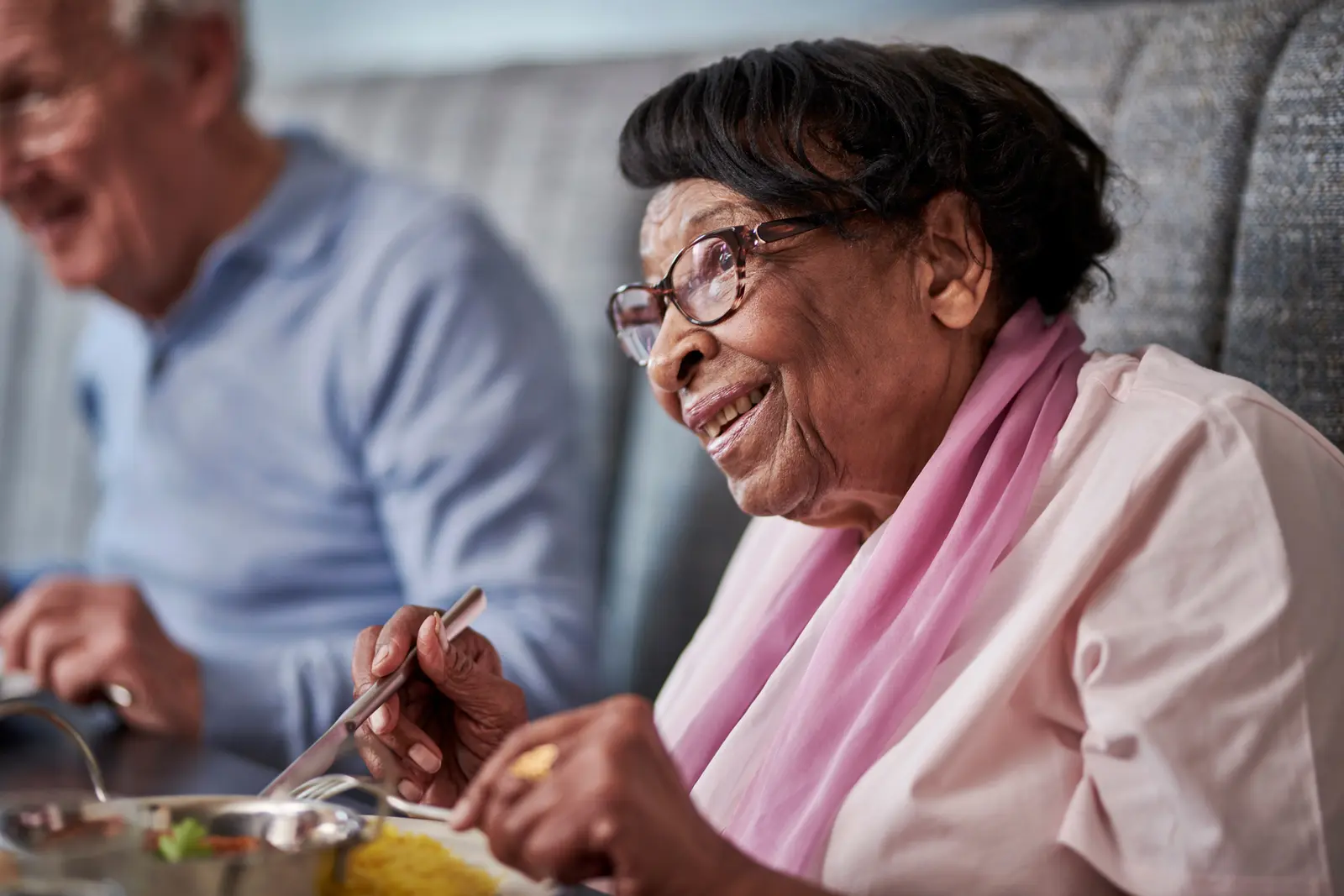 An older lady eating a plate of curry and rice