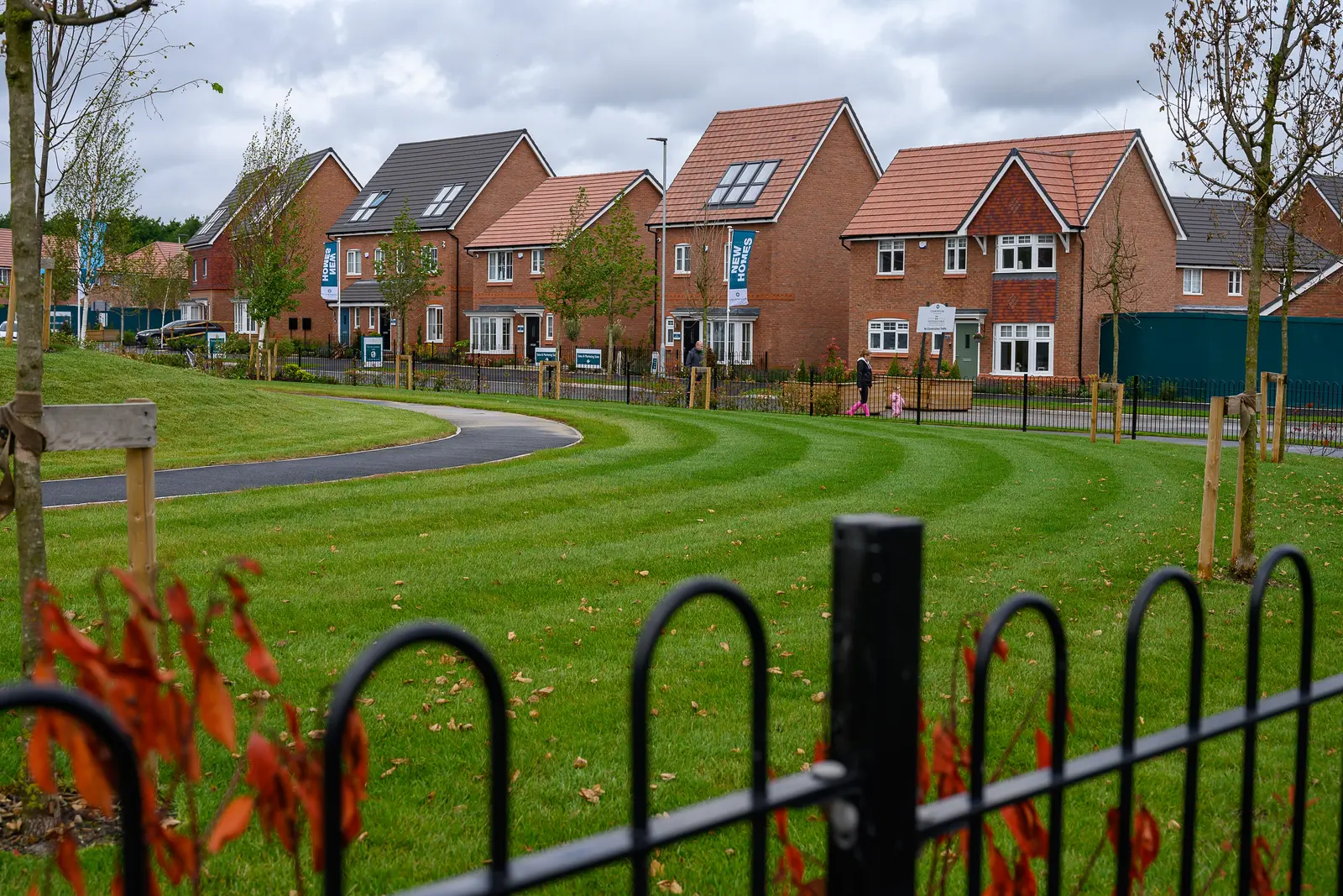 Green space in front of a row of detached show homes at a new development