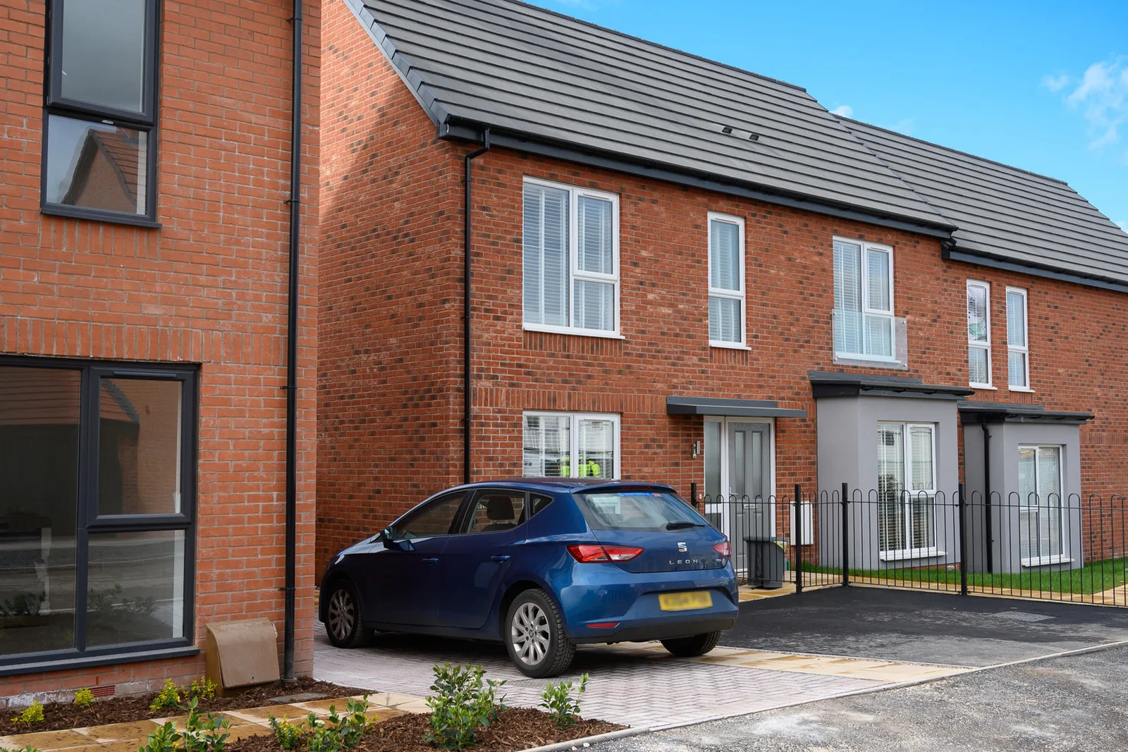 A blue car in the driveway of a home on a new development