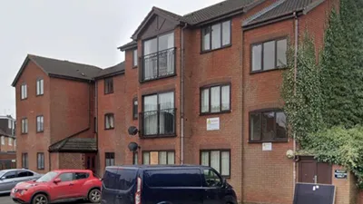 A three-storey residential building with Juliet balconies and parking at the front