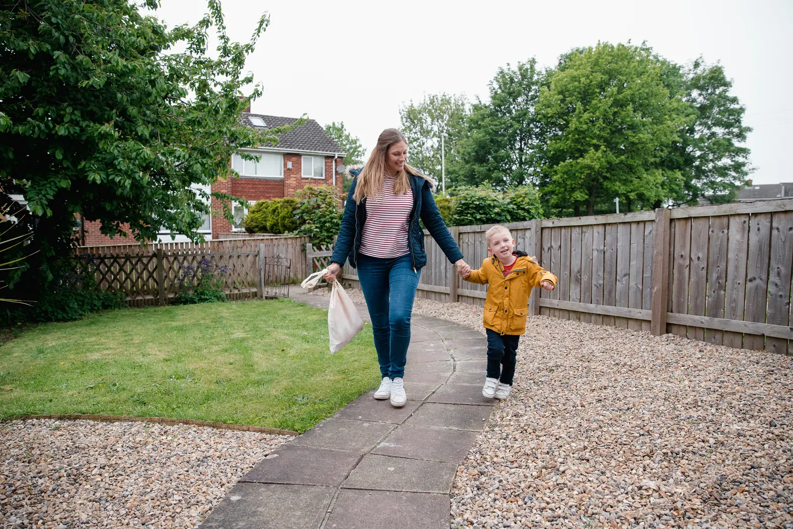 A young woman and a little boy are walking along a garden path holding hands